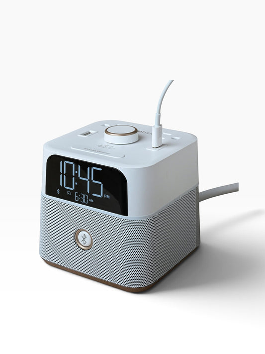 Valiant Products CubieBlue white charging alarm clock with Bluetooth speaker, USB-C and USB-A ports on a nightstand.