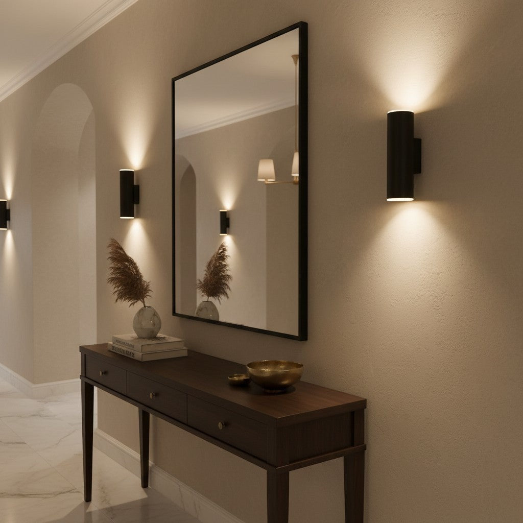 Valiant Products Totem matte black LED wall sconce providing warm up and down lighting in a modern hallway interior.