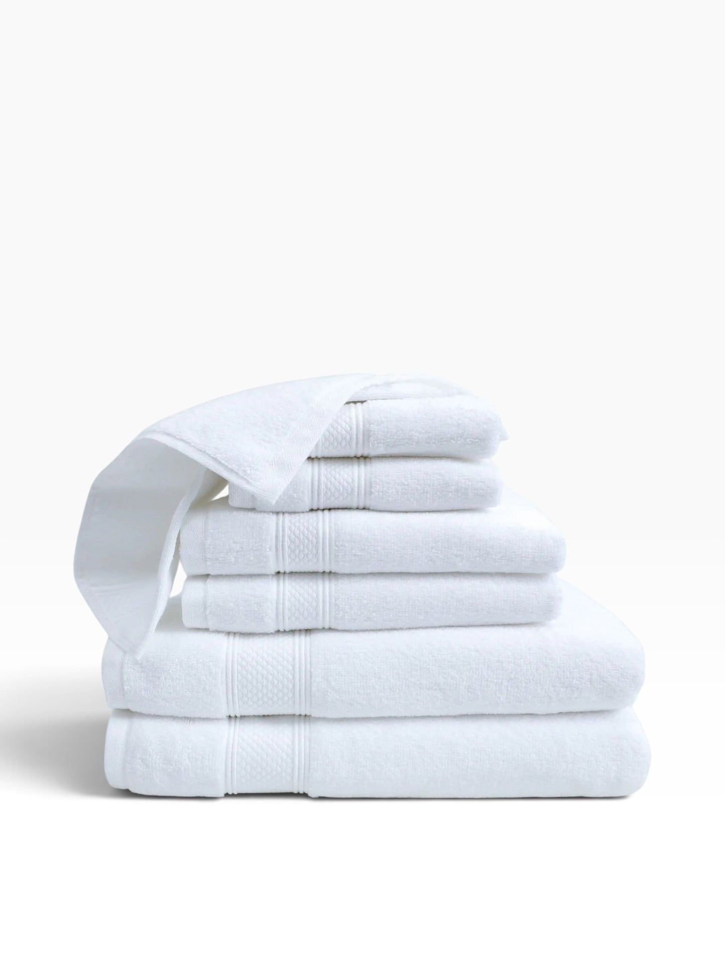 Valiant Products Atelier Zen white cotton bath towels with elegant dobby borders stacked in a plush pile