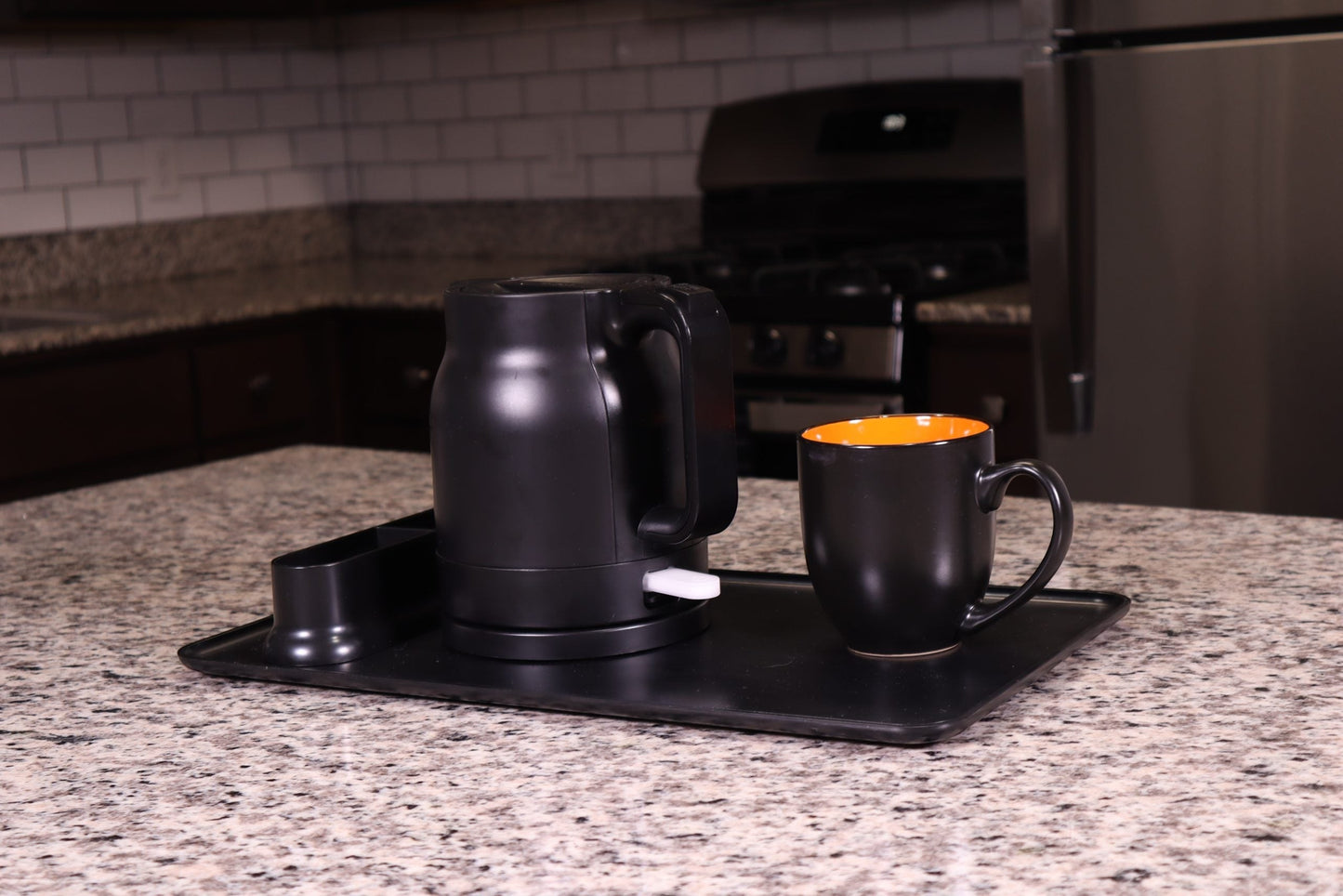 Valiant Products K-100 black electric kettle with anti-scalding insulation and matching mug on a serving tray