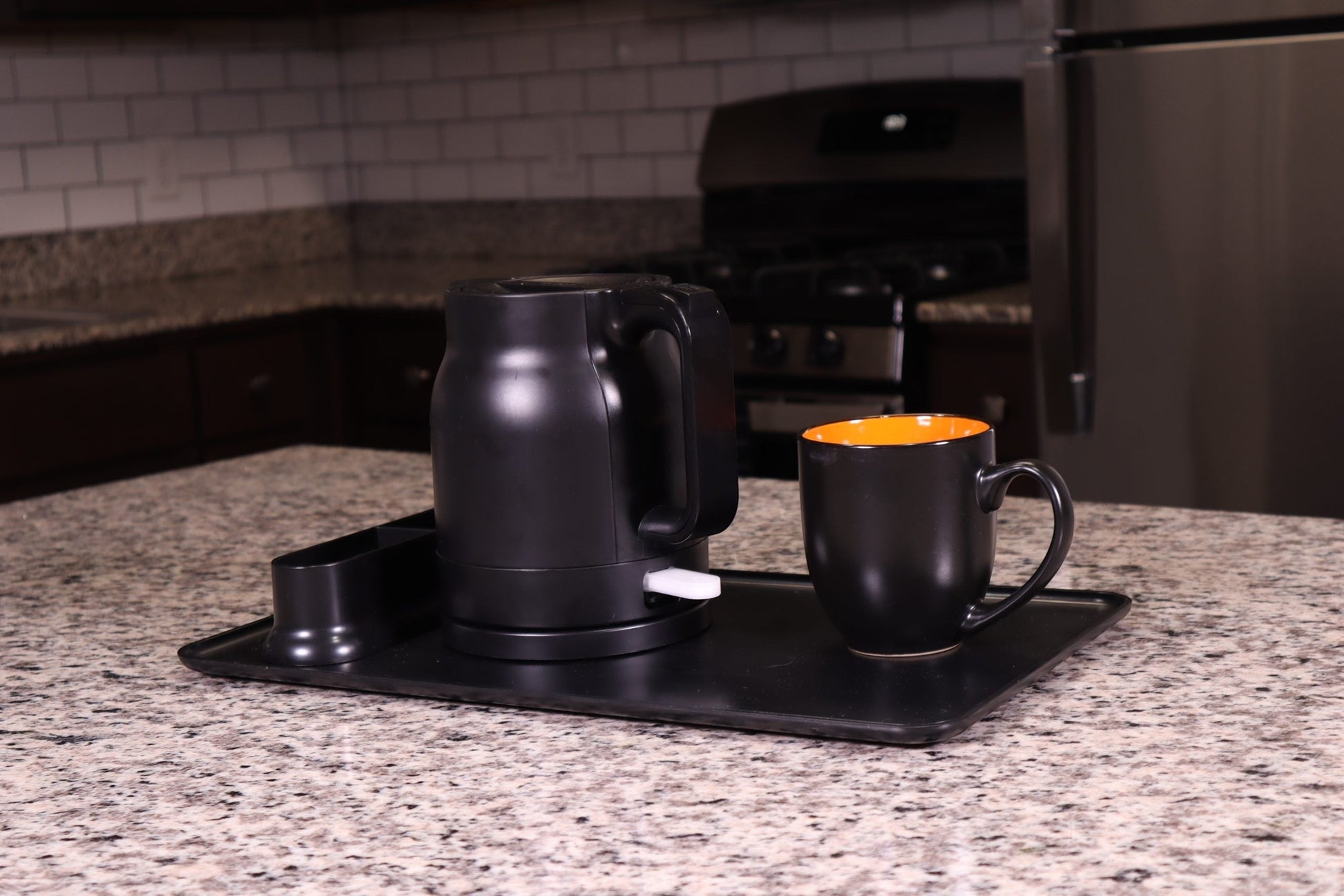 Valiant Products K-100 black electric kettle with anti-scalding insulation and matching mug on a serving tray
