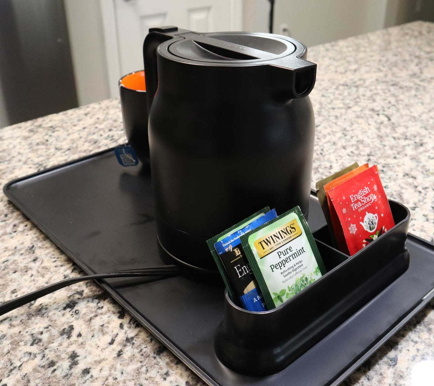 Valiant Products K-100 black electric kettle with tea bags on a serving tray for hotel hospitality use