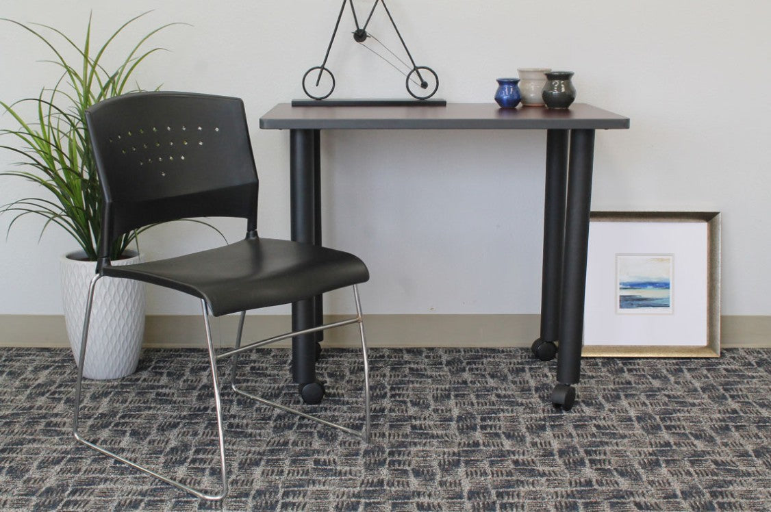 Valiant Products Kellan black polypropylene stack chair with a chrome frame and perforated backrest in an office space