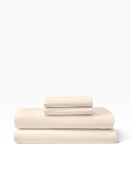 Valiant Products bone-colored T-200 thread count flat sheets folded in a stack for commercial hospitality use.