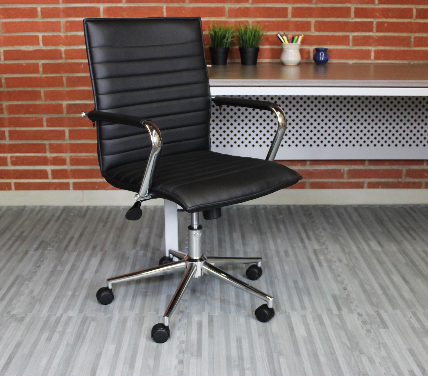 Valiant Products Brantley ergo chair in black PVC vinyl with fixed chrome arms and a sturdy chrome base.