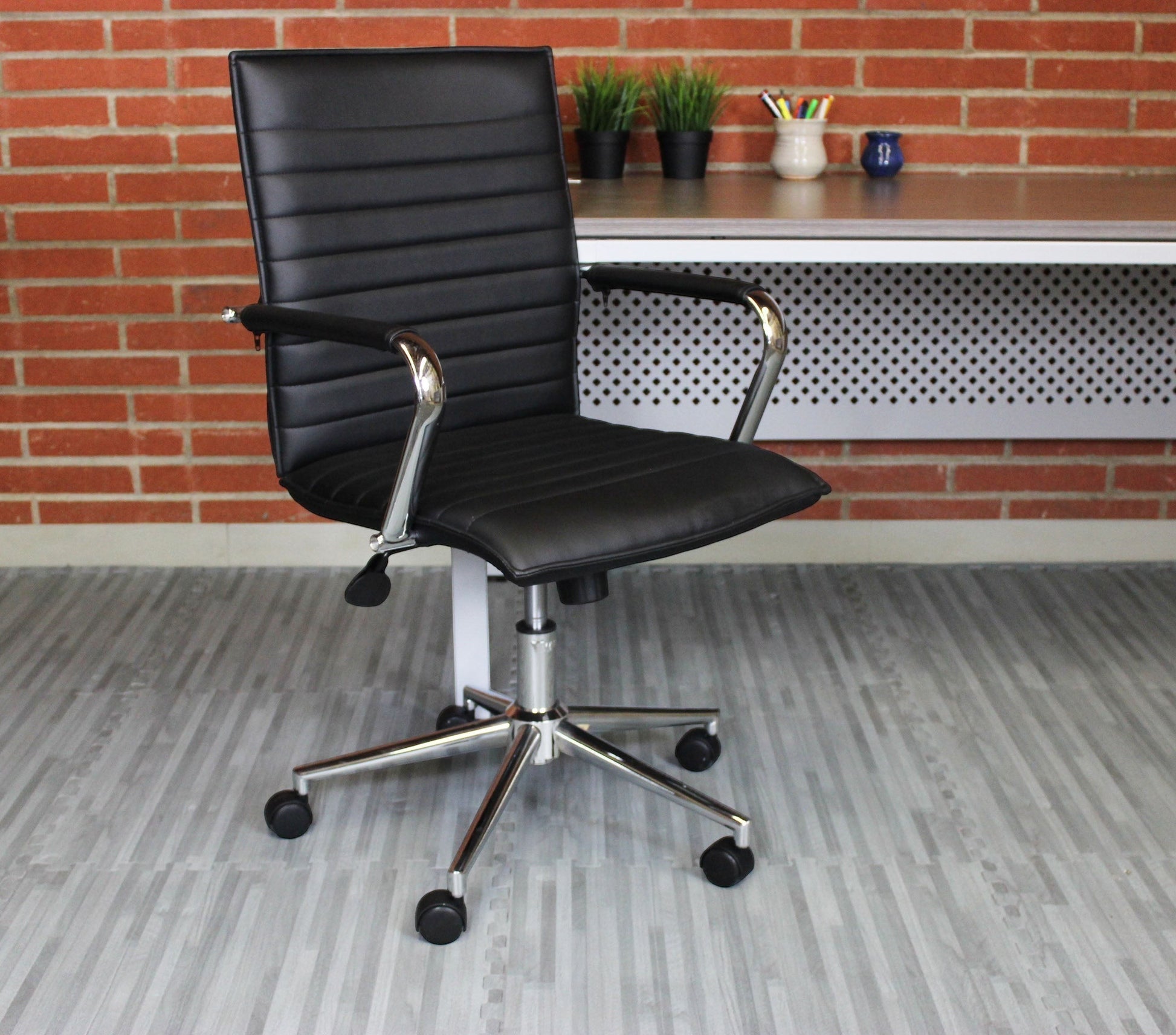 Valiant Products Brantley ergo chair in black PVC vinyl with fixed chrome arms and a sturdy chrome base.