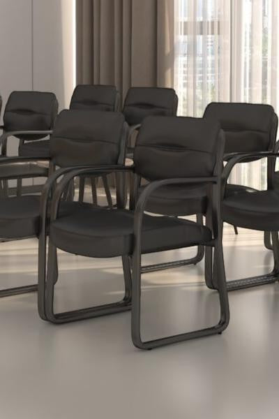 Valiant Products Conrad black leather guest chairs with sled bases and contoured cushions in a modern office setting.