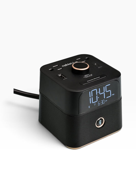 Valiant Products CubieBlue black hotel alarm clock with Bluetooth speaker, USB-C, USB-A ports, and power outlets.