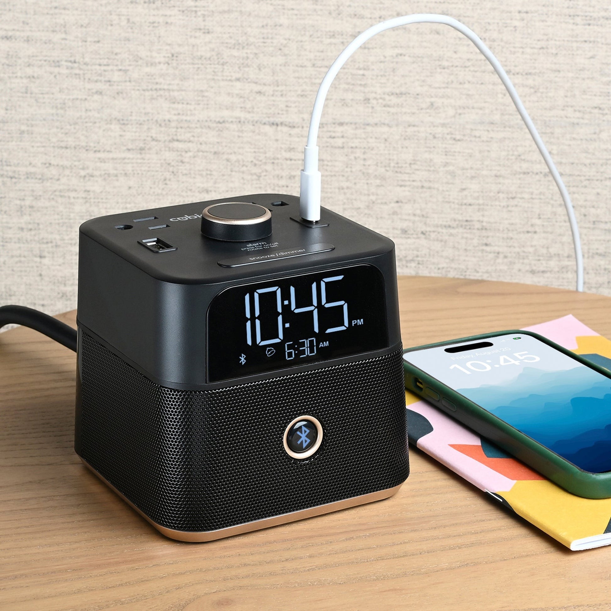 Valiant Products CubieBlue black charging alarm clock with Bluetooth speaker, USB ports, and a smartphone charging.
