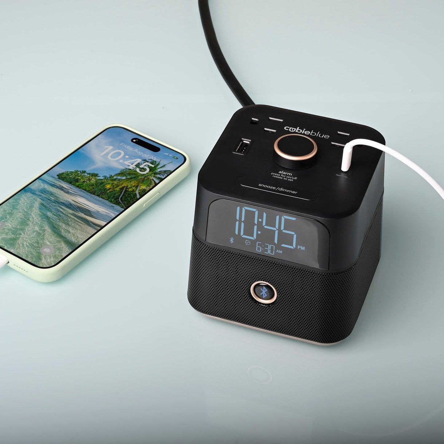 Valiant Products CubieBlue black charging alarm clock with Bluetooth speaker, USB ports, and a smartphone charging.