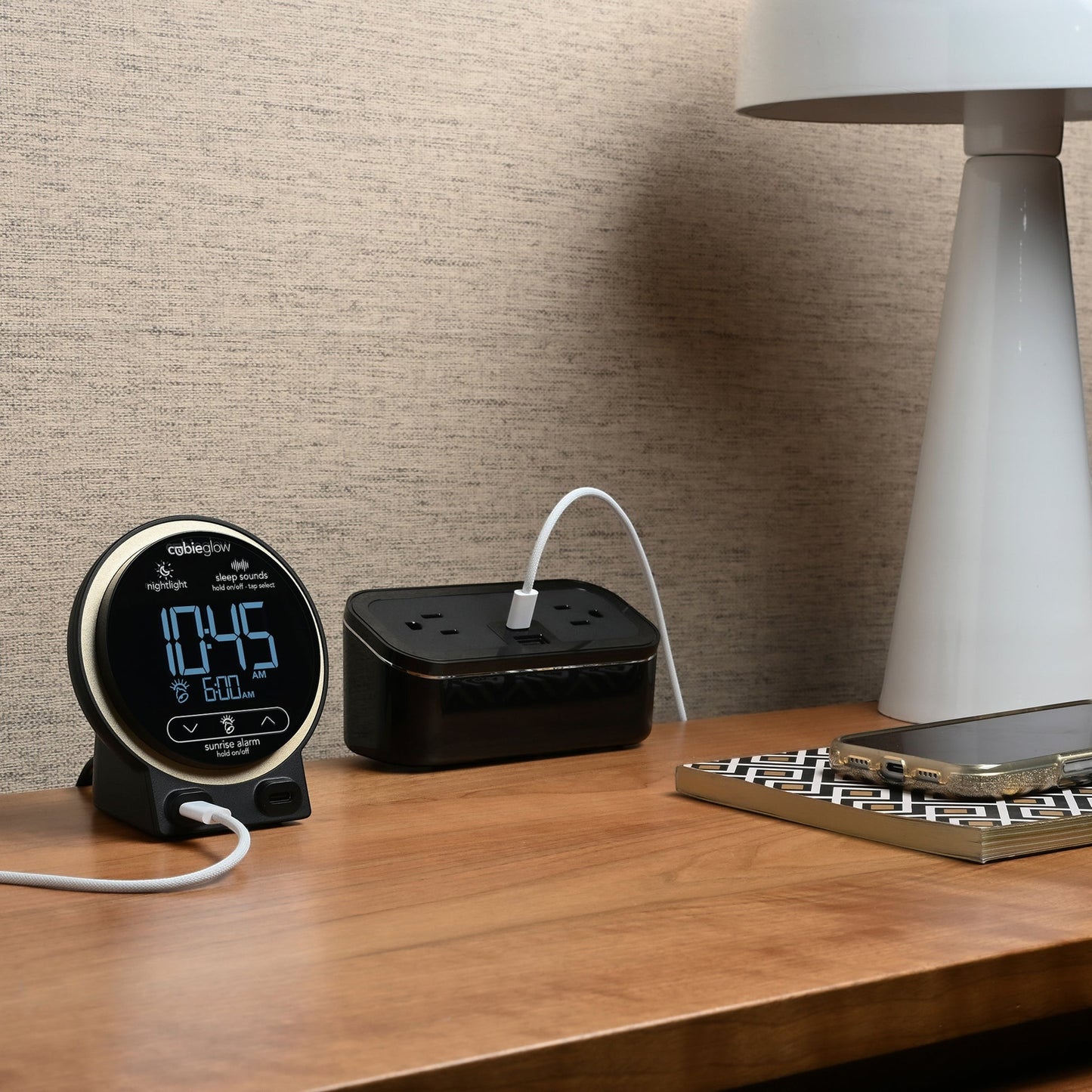 Valiant Products CubieGlow black charging alarm clock with USB-C ports and digital display on a hotel nightstand