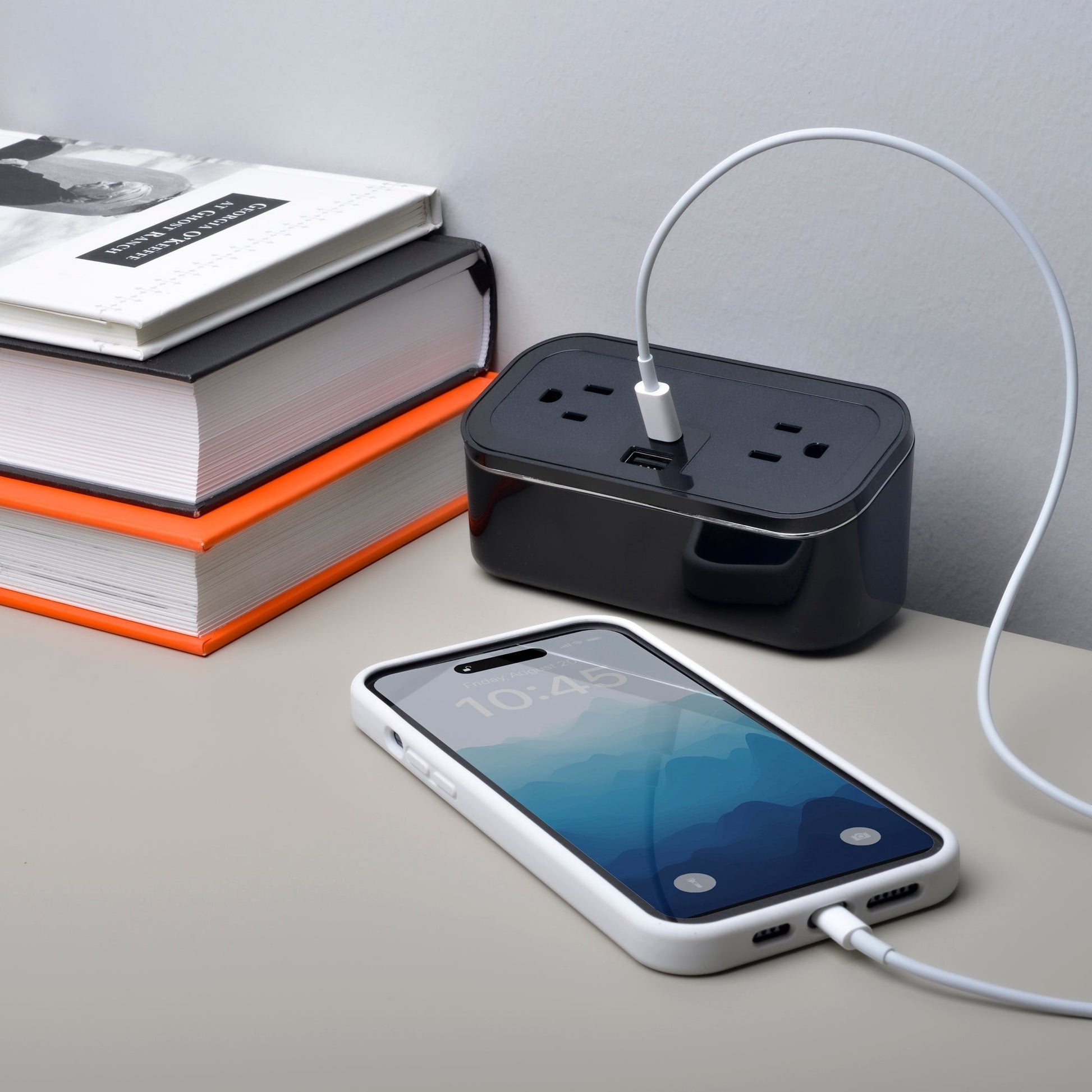 Valiant Products CubieMini black charging block with two outlets, USB-A and USB-C ports, charging a smartphone.