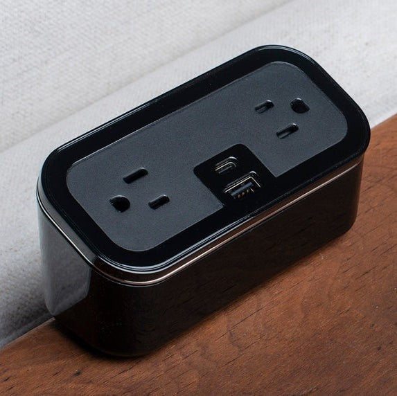 Valiant Products CubieMini black charging block with two power outlets, USB-A, and USB-C ports on a wooden surface