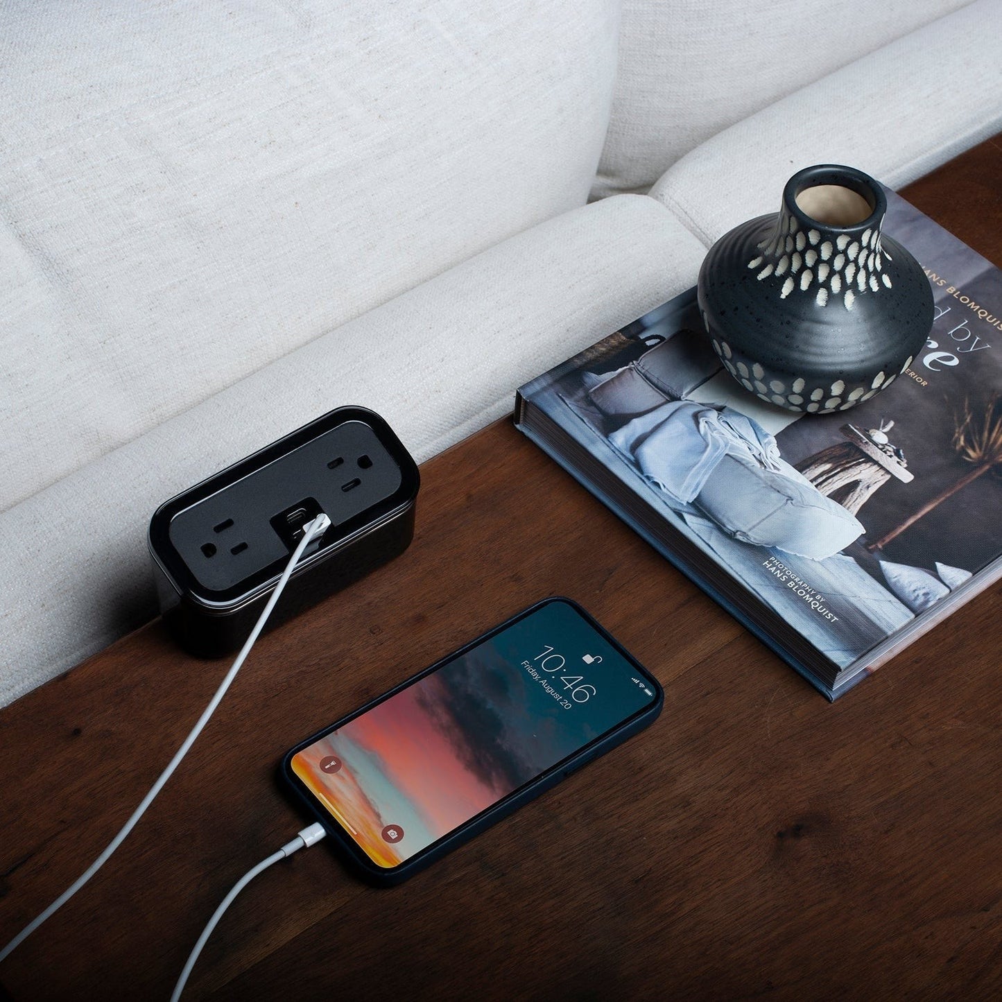 Valiant Products CubieMini black charging block with USB ports and power outlets on a wooden nightstand with a phone.