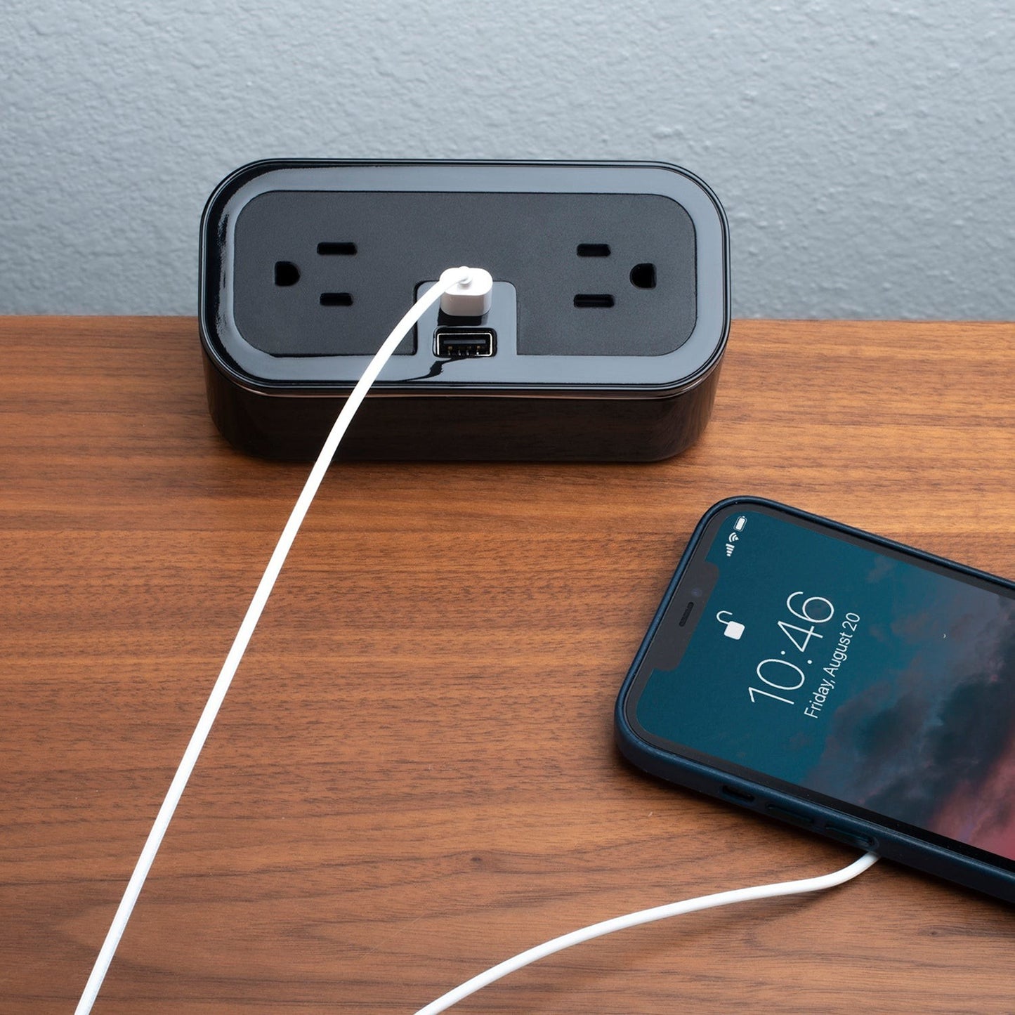 Valiant Products CubieMini black charging block with two power outlets, USB-A and USB-C ports, charging a smartphone.