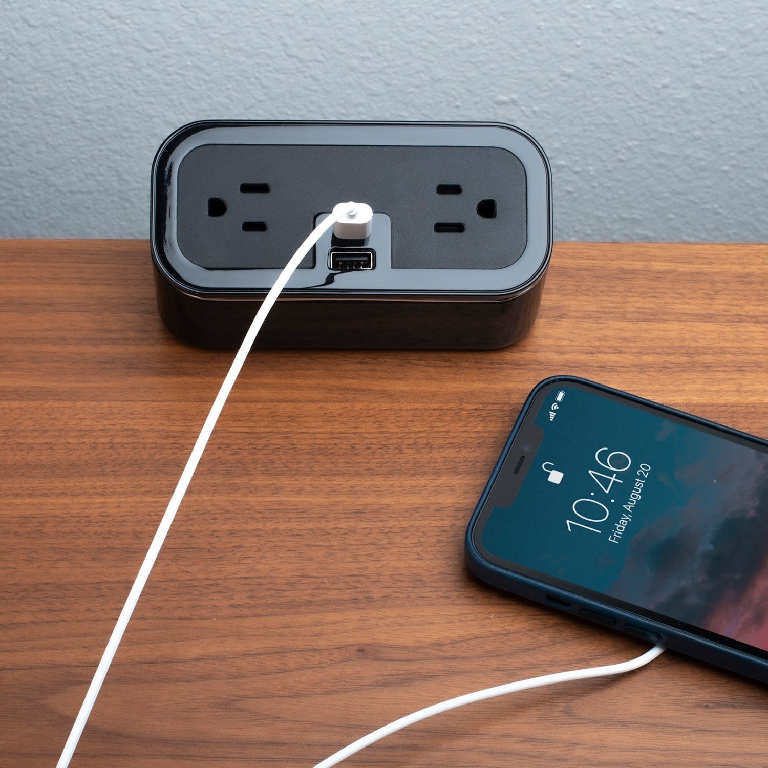 Valiant Products CubieMini black charging block with two power outlets, USB-A and USB-C ports, charging a smartphone.