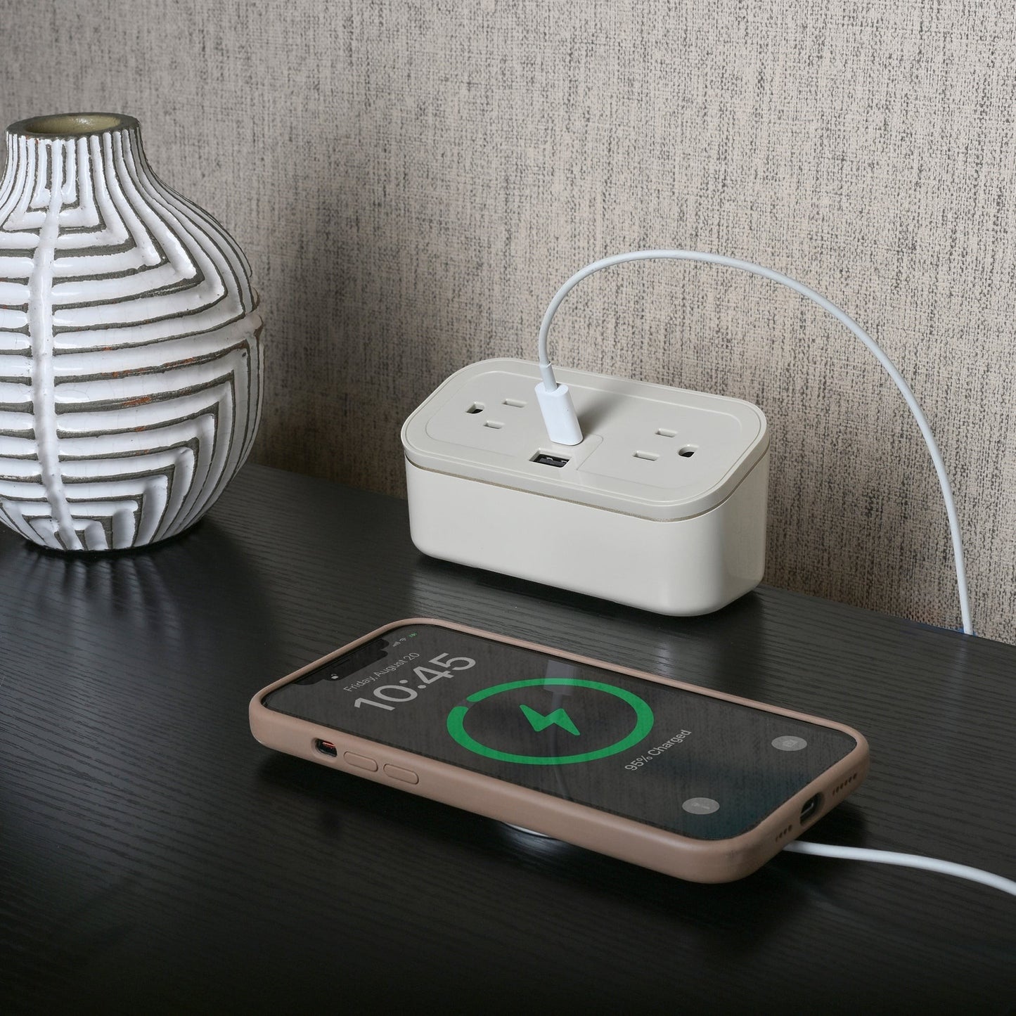 Valiant Products CubieMini latte charging block with USB ports and outlets on a dark nightstand with a smartphone