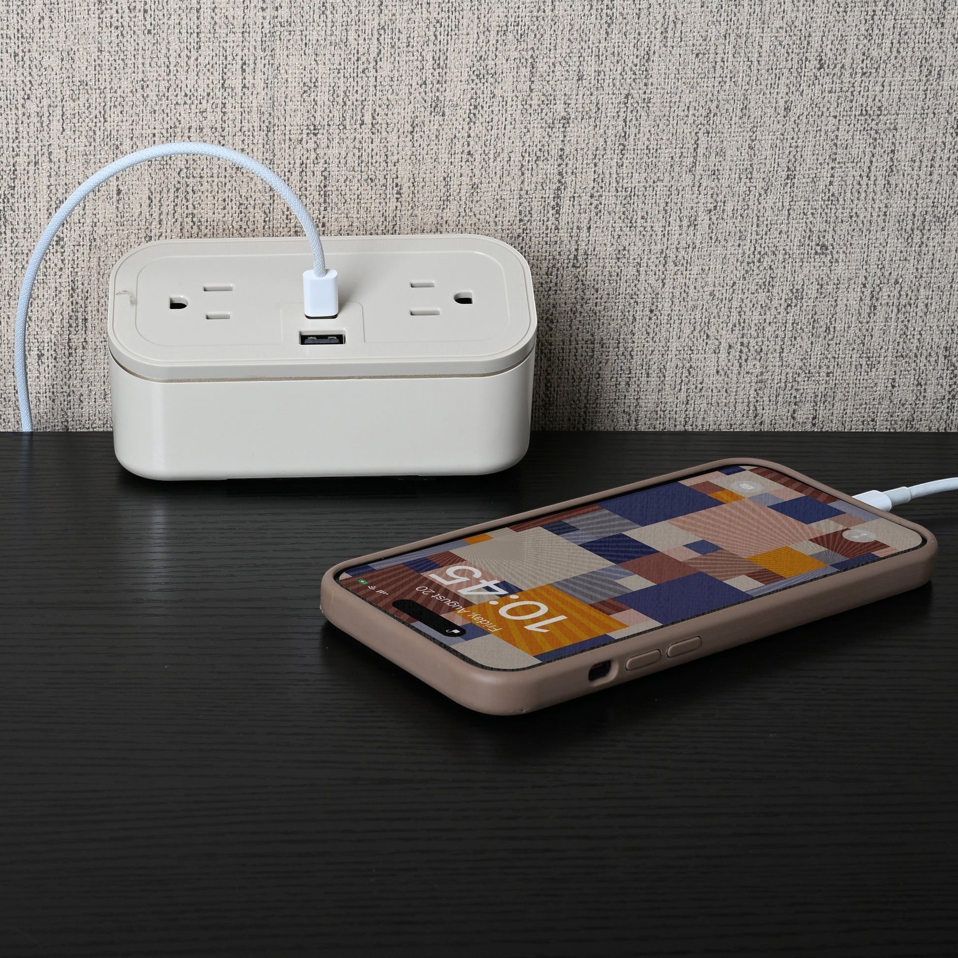 Valiant Products CubieMini latte charging block with two power outlets and USB ports charging a smartphone on a desk.