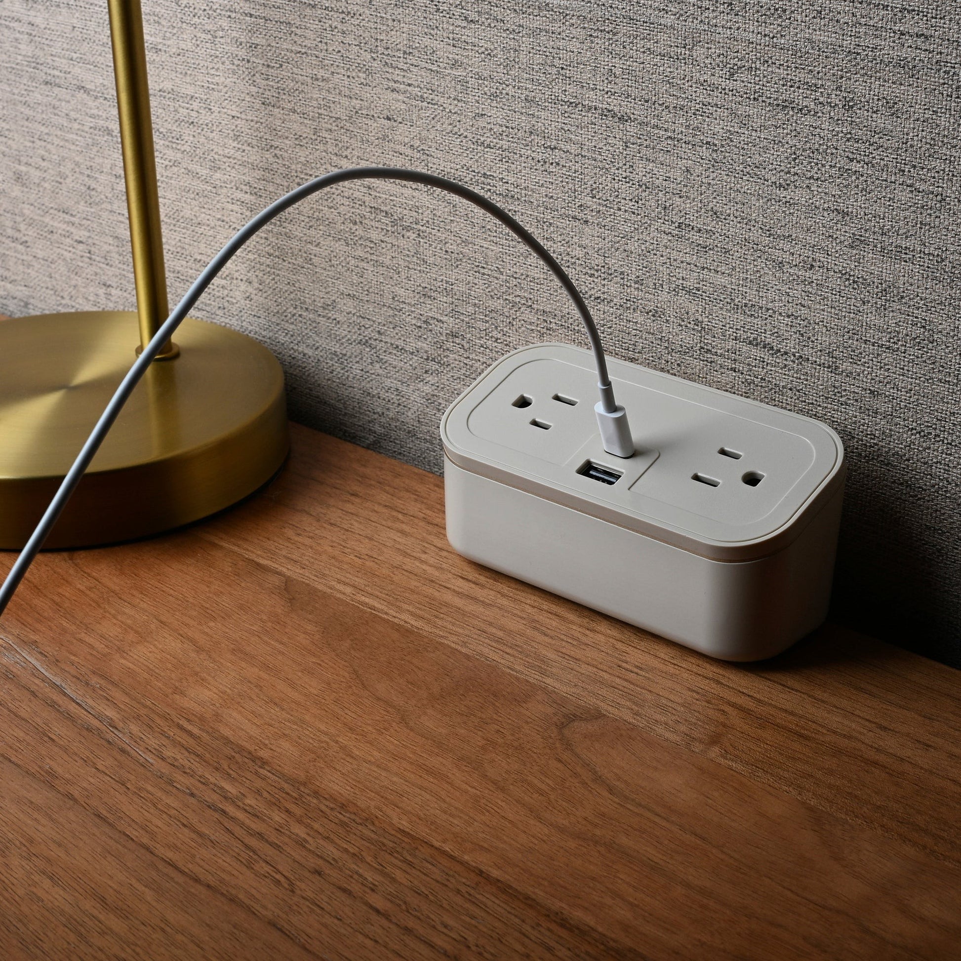 Valiant Products CubieMini latte charging block with two power outlets, USB-A and USB-C ports on a wooden nightstand.