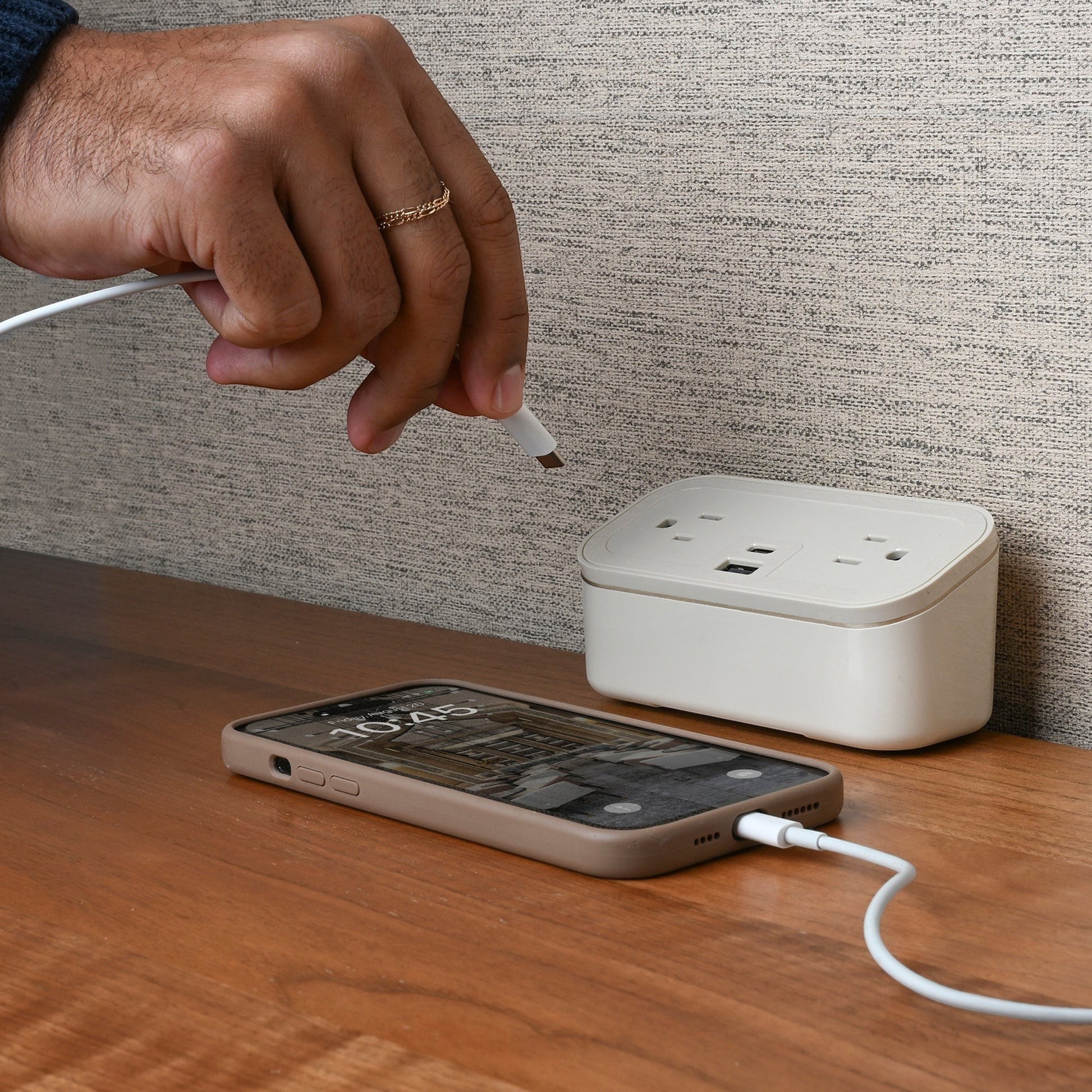 Valiant Products CubieMini white charging block with USB-C and USB-A ports on a wooden nightstand with a smartphone.