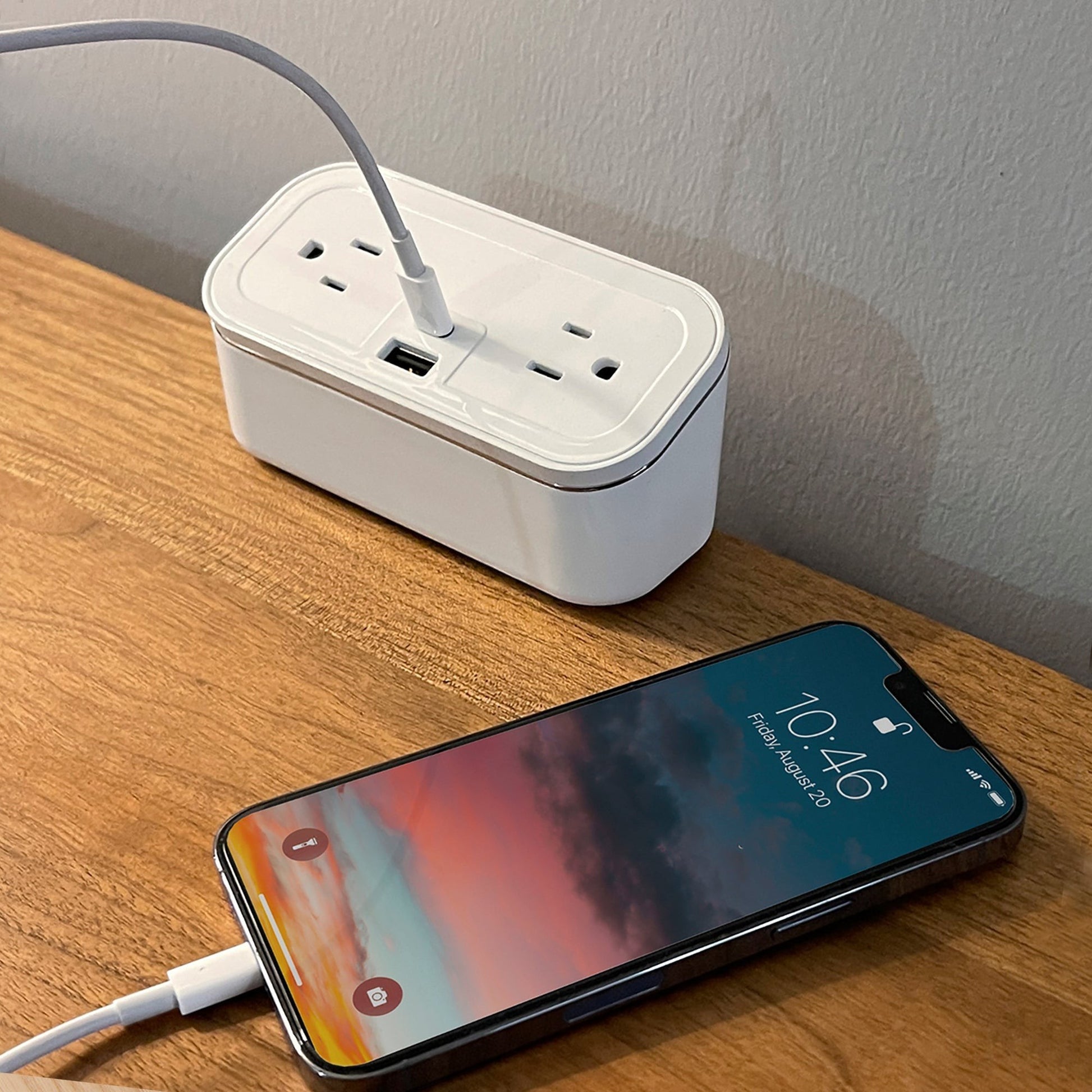 Valiant Products white CubieMini charging block with USB ports and power outlets on a wooden hotel nightstand