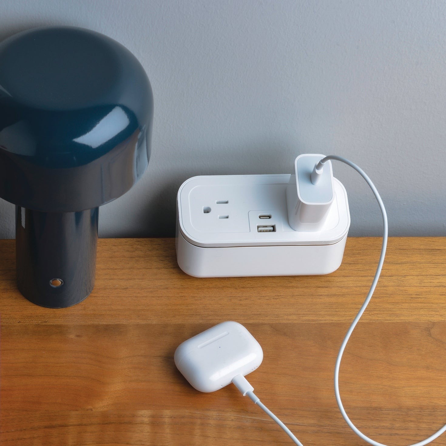 Valiant Products CubieMini white charging block with USB-C, USB-A, and power outlets on a wooden hotel nightstand.