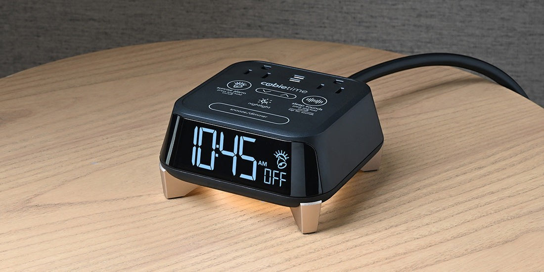 Valiant Products CubieTime Zen black alarm clock with digital display, USB ports, and power outlets on a wooden table.