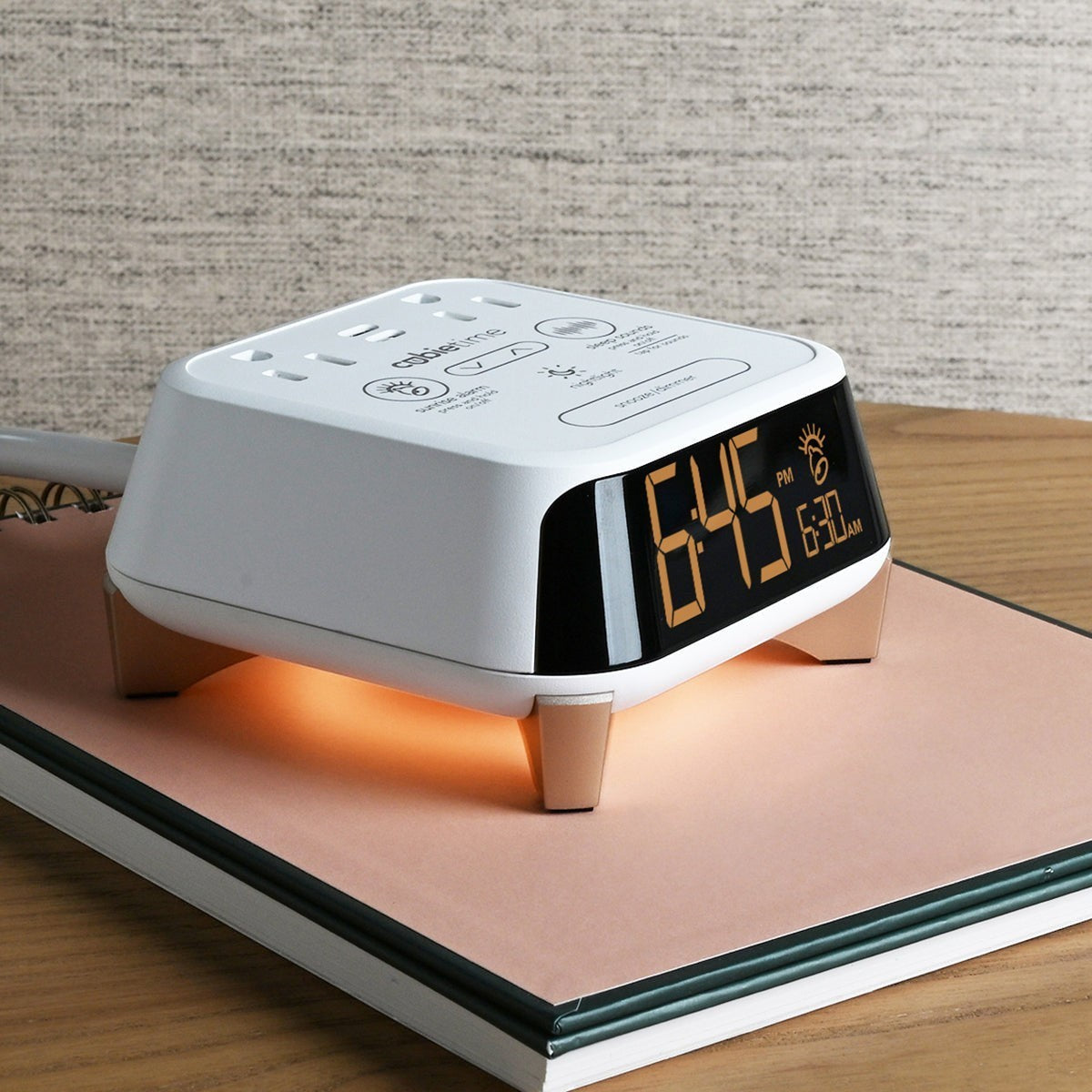 Valiant Products CubieTime Zen white alarm clock with digital display, nightlight, and charging ports on a notebook.