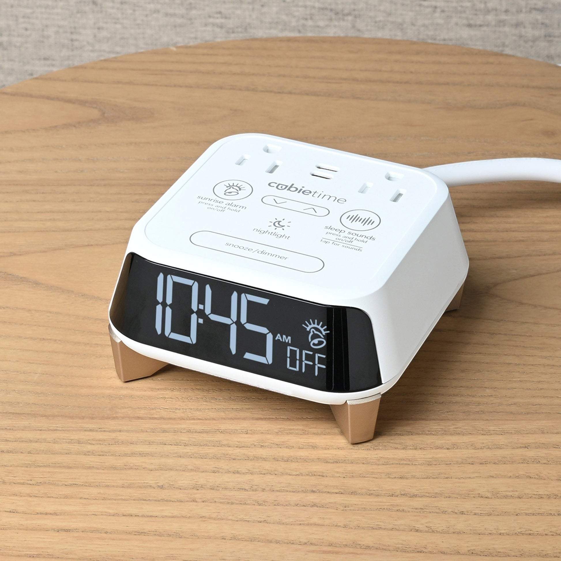 Valiant Products CubieTime Zen white alarm clock with USB ports and digital display on a wooden nightstand