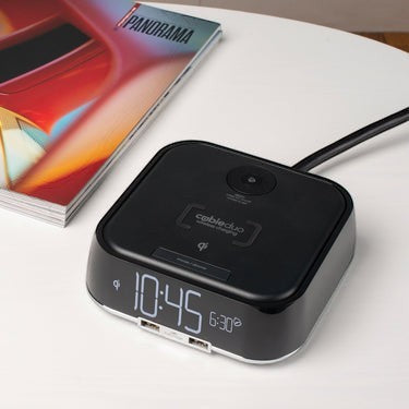 Valiant Products CubieTrio black alarm clock with wireless charging pad and USB ports on a white nightstand