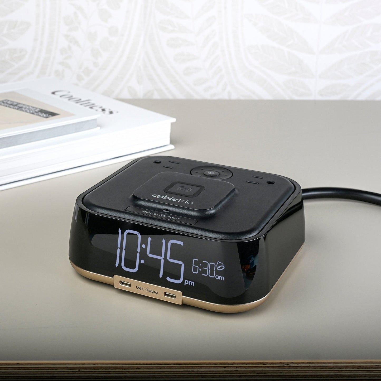 Valiant Products CubieTrio black and champagne alarm clock with wireless charging pad and USB-C ports on a nightstand