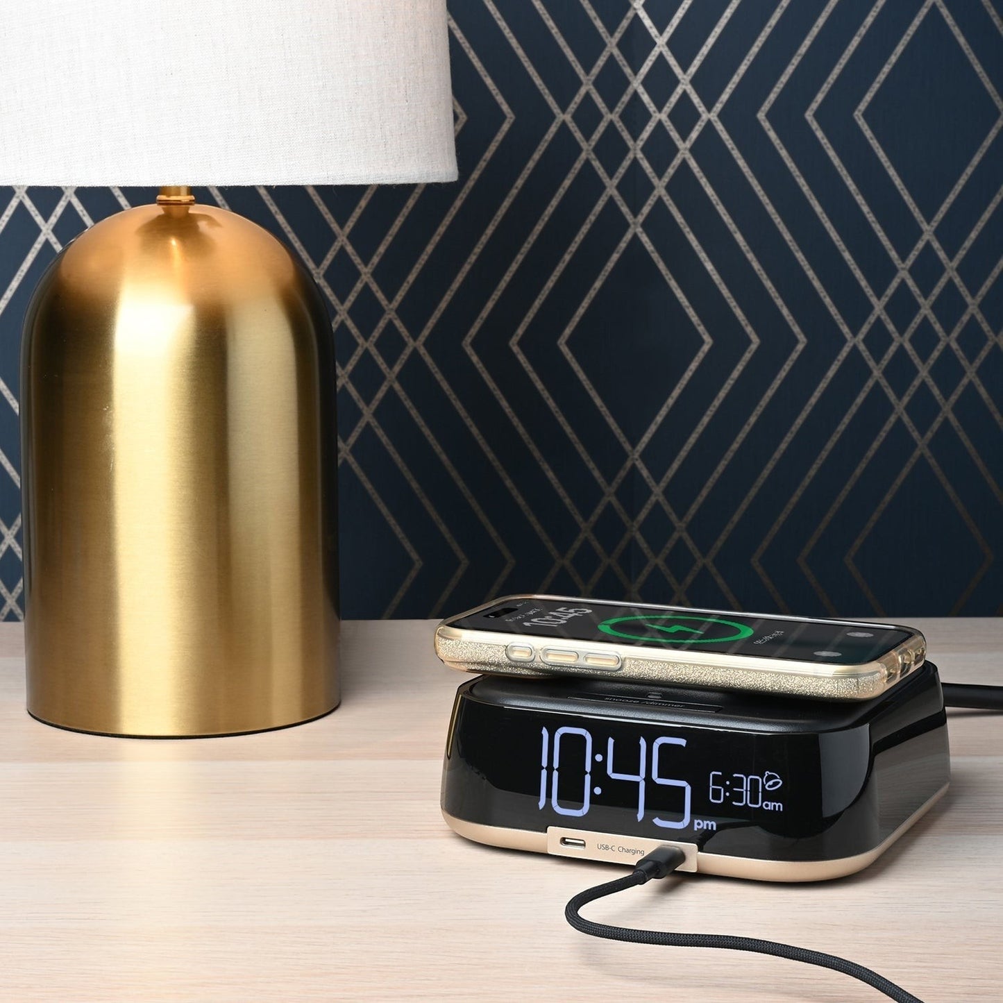 Valiant Products CubieTrio black and champagne alarm clock with wireless phone charging on a hotel nightstand