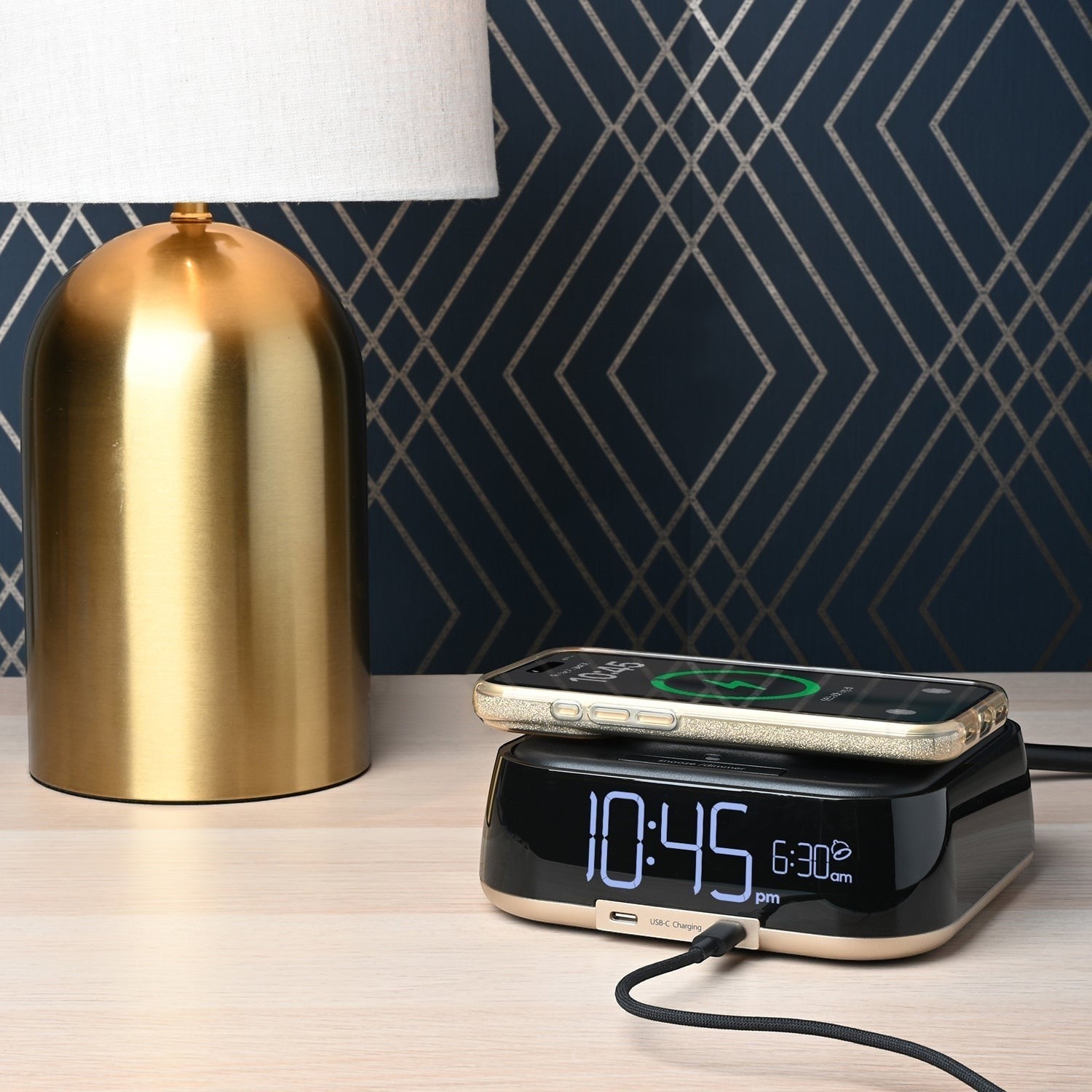 Valiant Products CubieTrio black and champagne alarm clock with wireless phone charging on a hotel nightstand