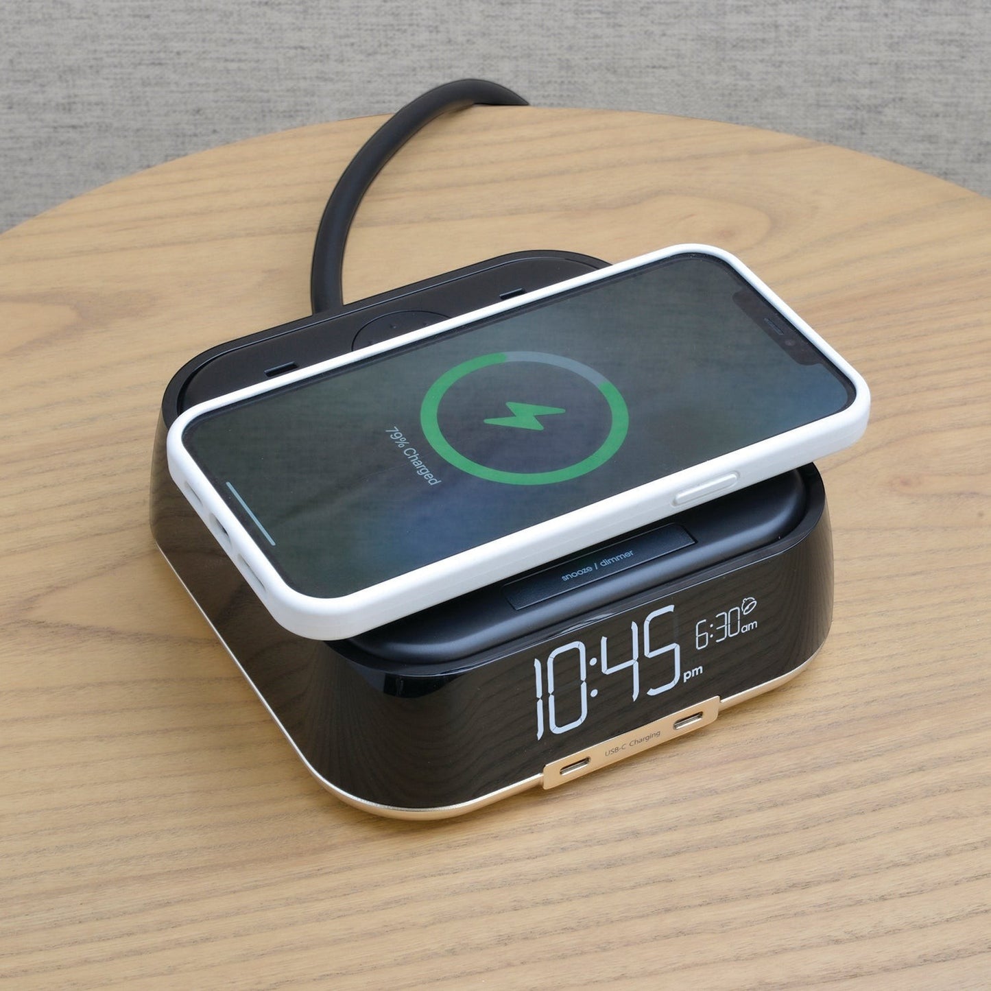 Valiant Products CubieTrio black alarm clock with wireless smartphone charging on a wooden nightstand