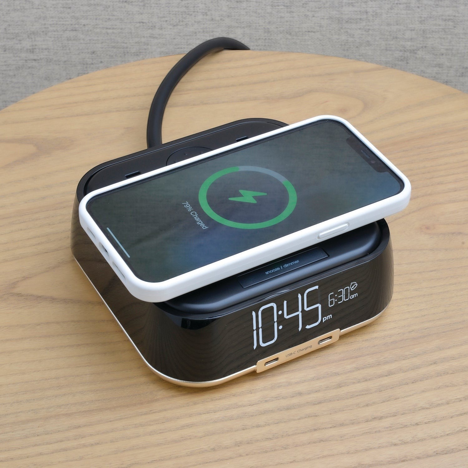 Valiant Products CubieTrio black alarm clock with wireless smartphone charging on a wooden nightstand
