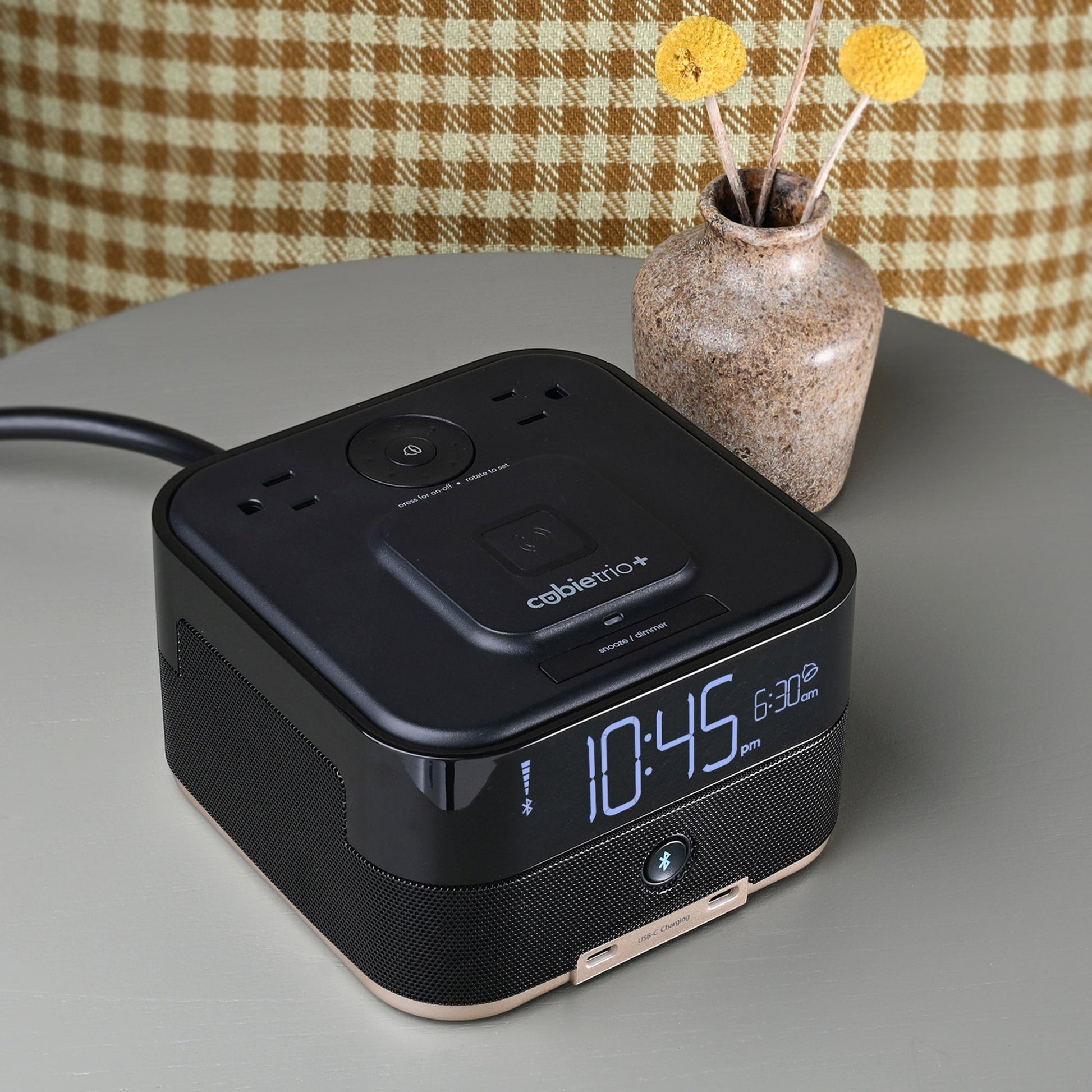 Valiant Products CubieTrio+ black alarm clock with wireless charging, Bluetooth speaker, and USB-C ports on a table.
