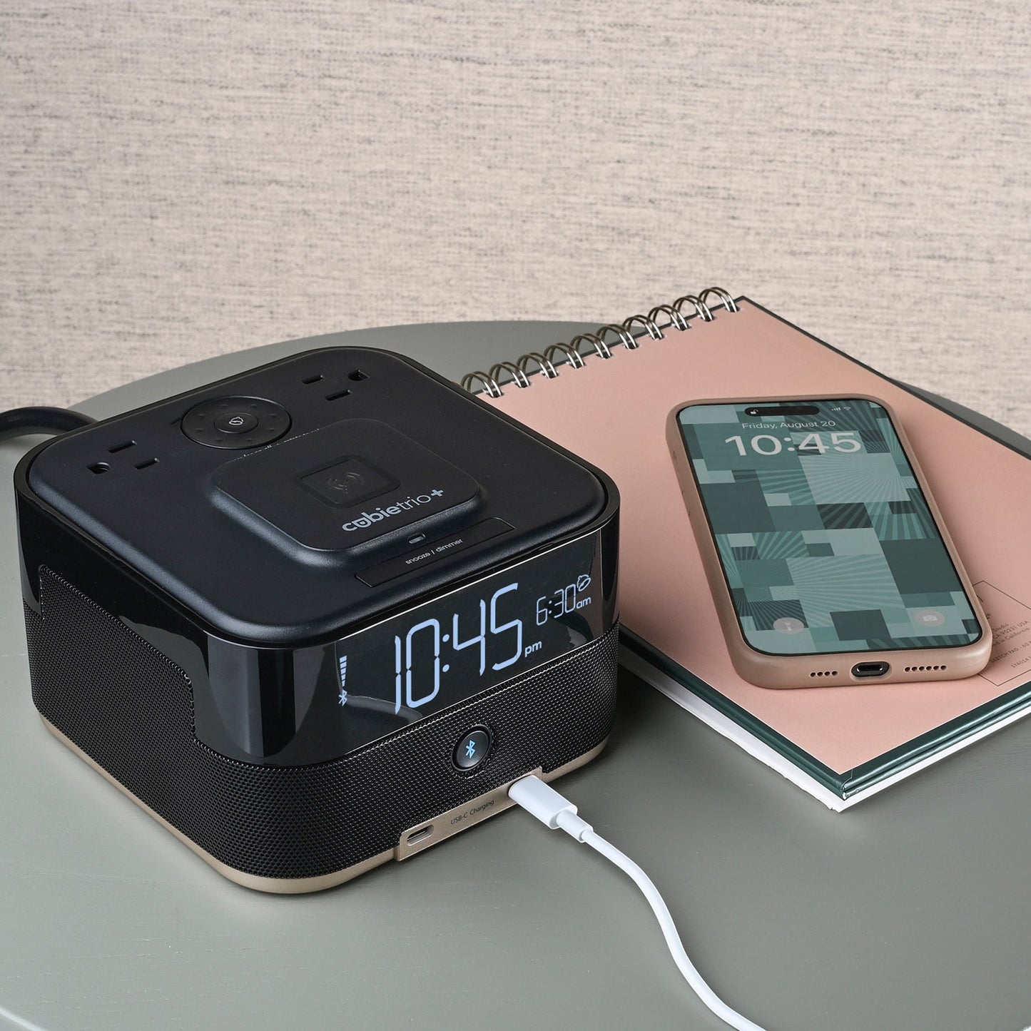 Valiant Products CubieTrio+ black alarm clock with wireless charging, USB-C ports, and Bluetooth speaker on a desk.