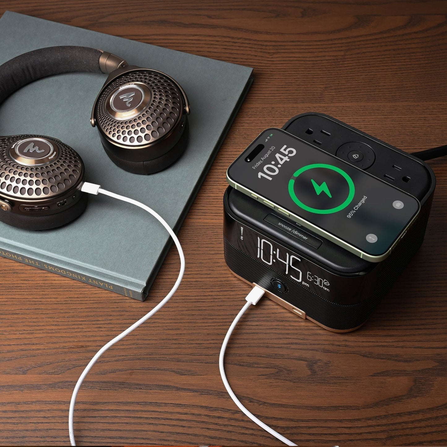 Valiant Products CubieTrio+ black charging alarm clock with wireless phone charging and wired headphones on a desk.