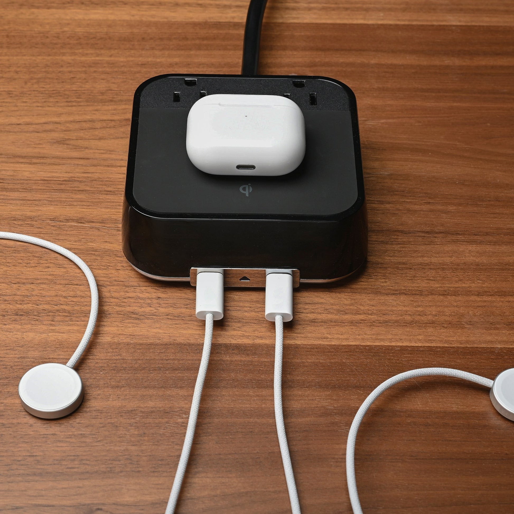 Valiant Products CubieVia black charging block with wireless Qi pad, two USB-C ports, and two AC outlets on wood desk