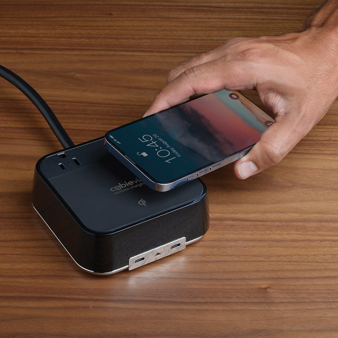Valiant Products CubieVia black charging block with wireless Qi pad, AC outlets, and USB-C ports on a wooden desk