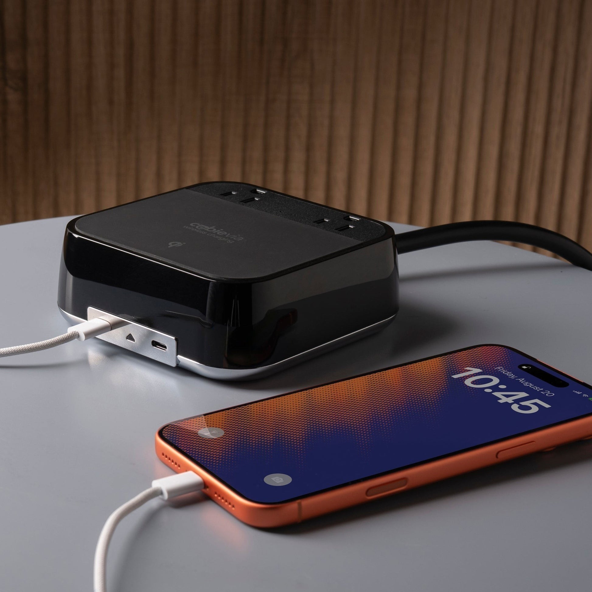 Valiant Products CubieVia black charging block with wireless Qi pad, two USB-C ports, and AC outlets on a table.
