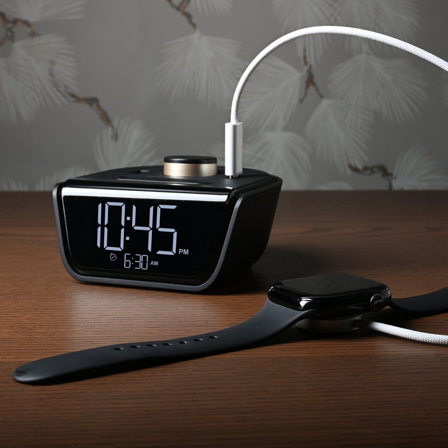 Valiant Products CubieWink black digital alarm clock with USB-C and USB-A charging ports on a wooden nightstand