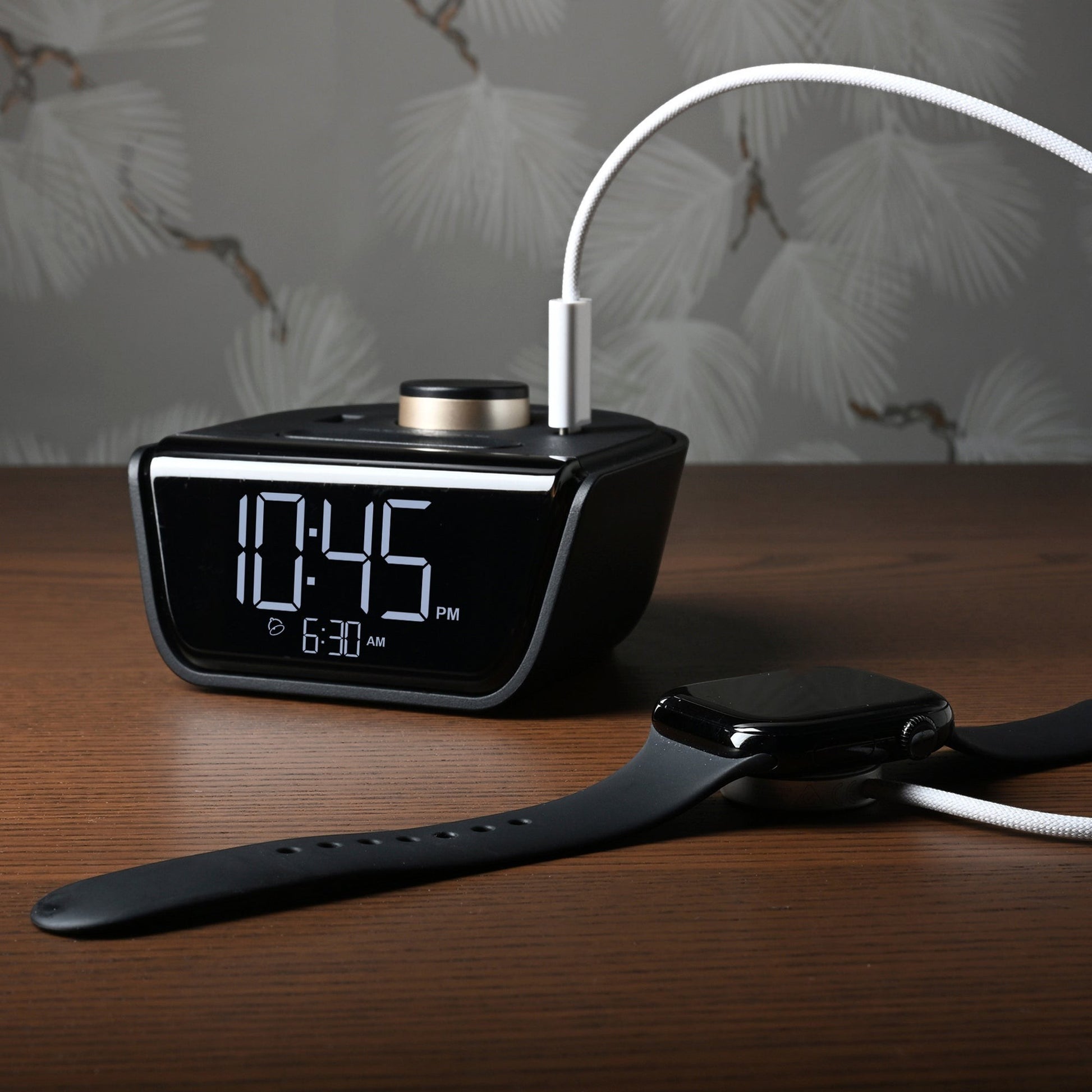Valiant Products CubieWink black digital alarm clock with USB-C and USB-A charging ports on a wooden nightstand