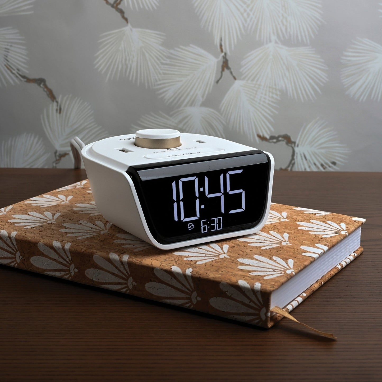 Valiant Products CubieWink white charging alarm clock with USB-A and USB-C ports sitting on a patterned book