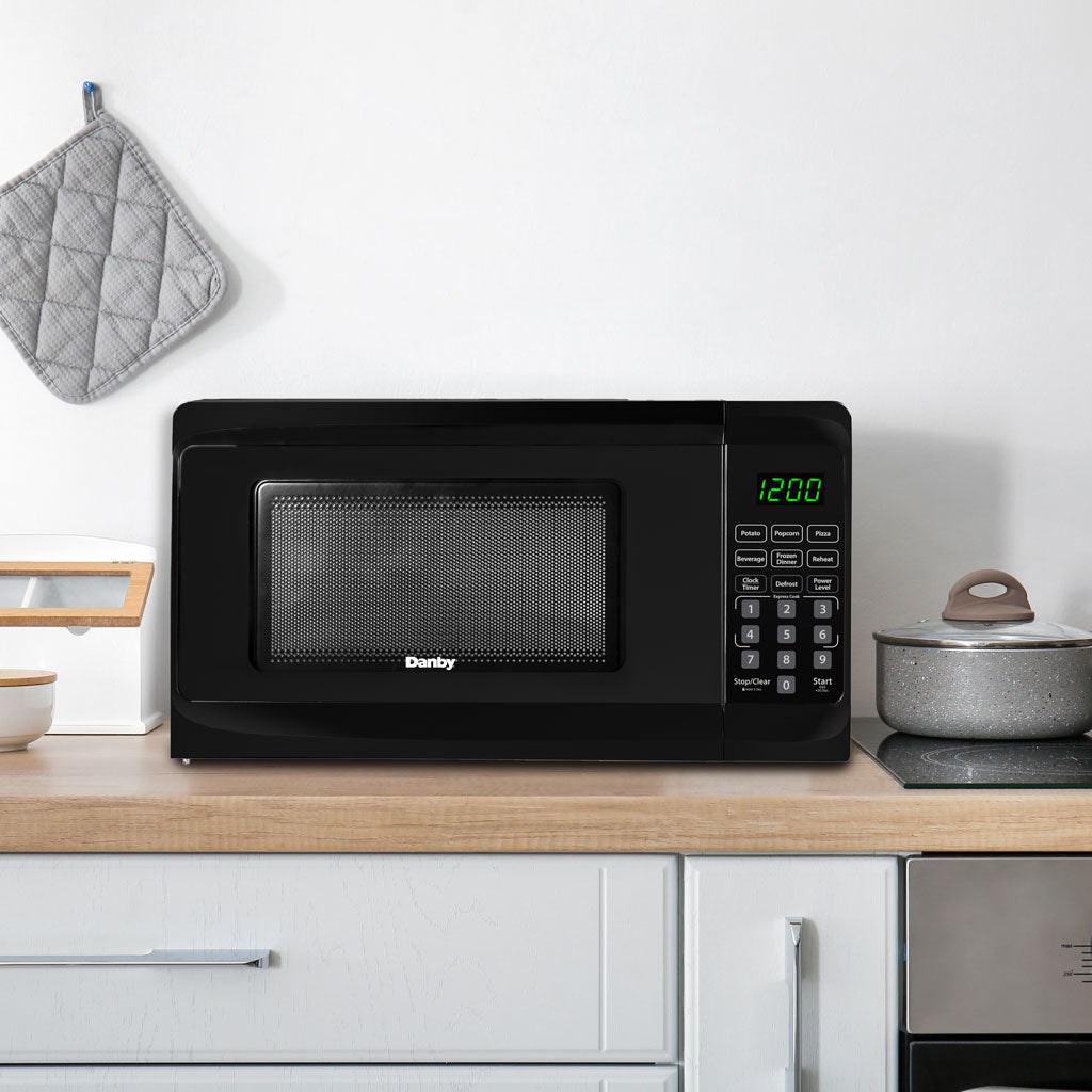 Valiant Products Danby 0.7 cu. ft. black countertop microwave with digital display and child safety lock on a counter.
