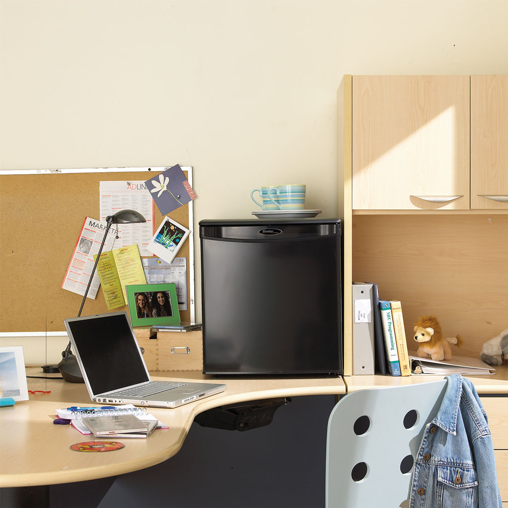 Valiant Products Danby 1.7 cu. ft. compact refrigerator in black, placed on a desk in a student dorm room setting.