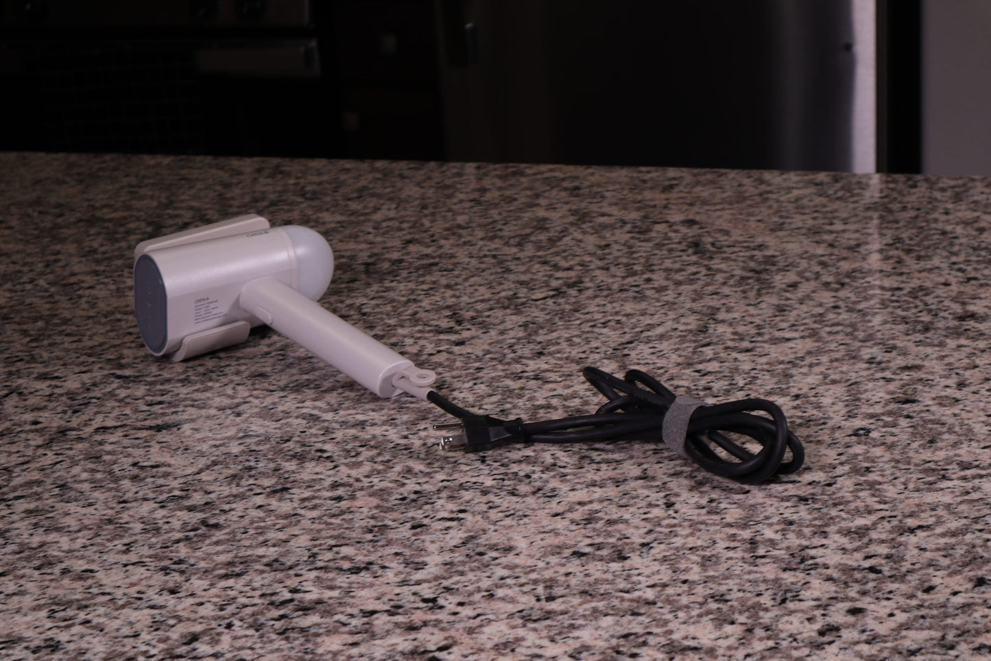 Valiant Products gray handheld garment steamer with a non-stick base plate and power cord on a granite countertop