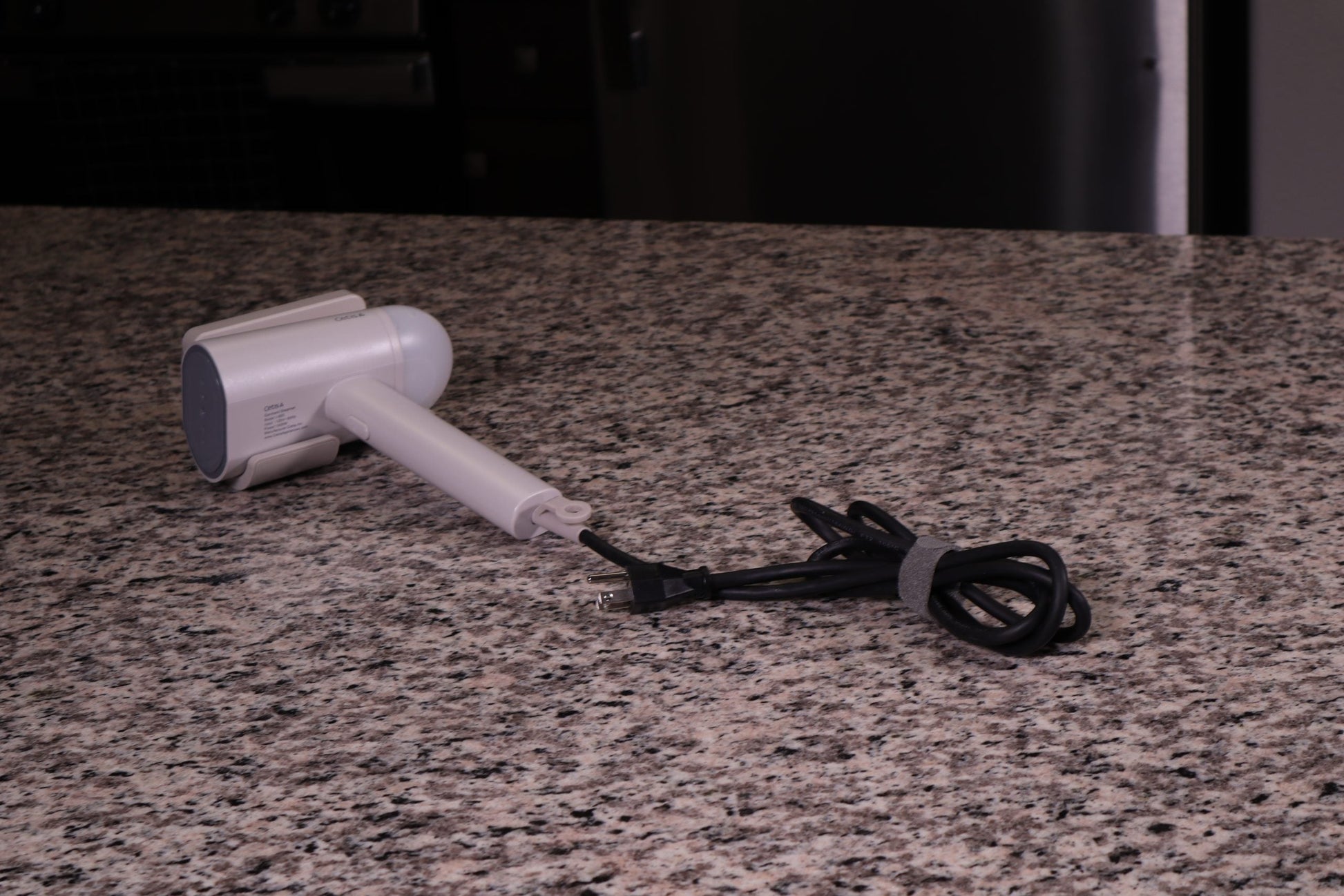 Valiant Products gray handheld garment steamer with a non-stick base plate and power cord on a granite countertop