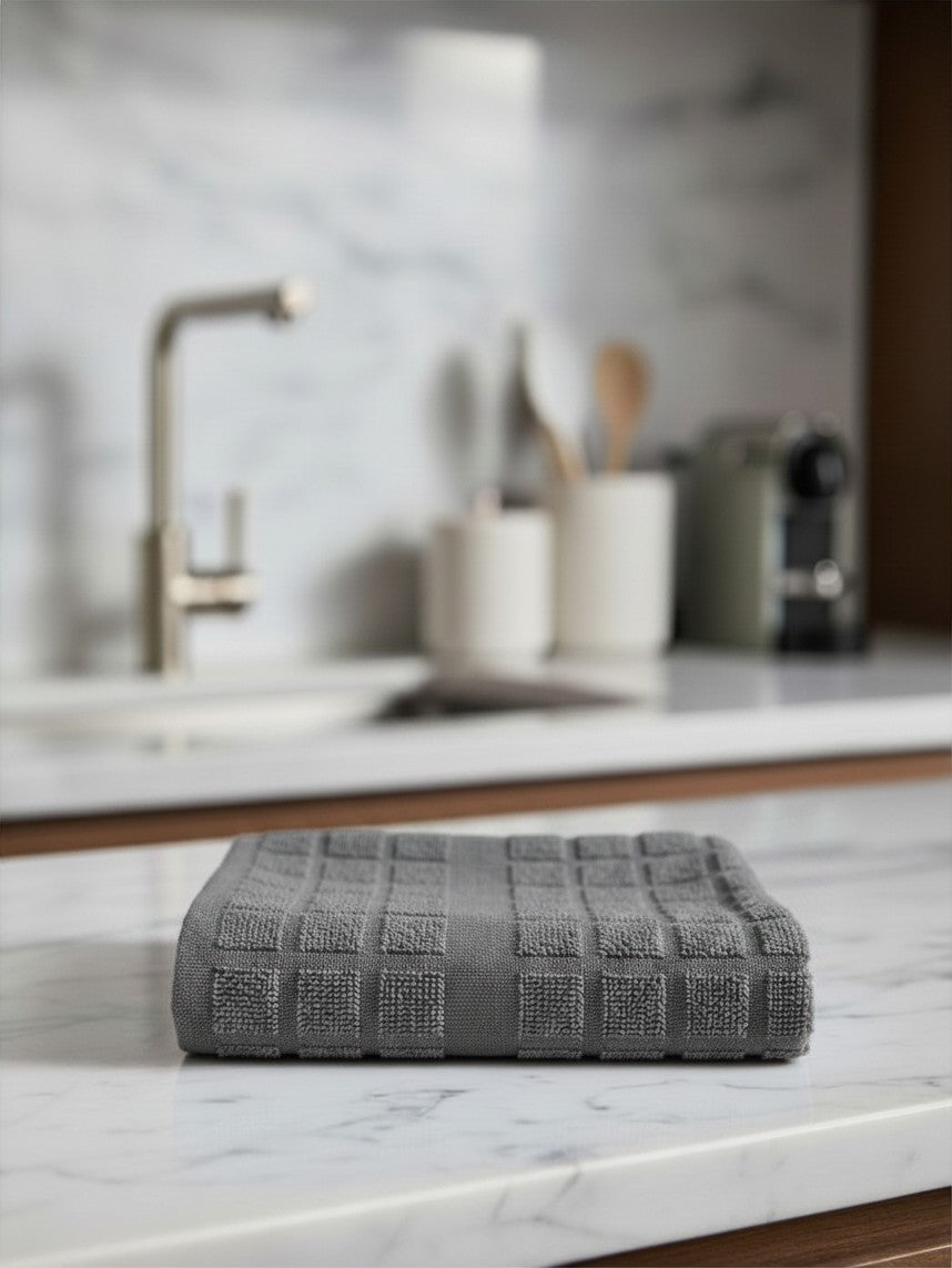 Valiant Products grey cotton dish cloth with textured square pattern on a marble kitchen countertop.