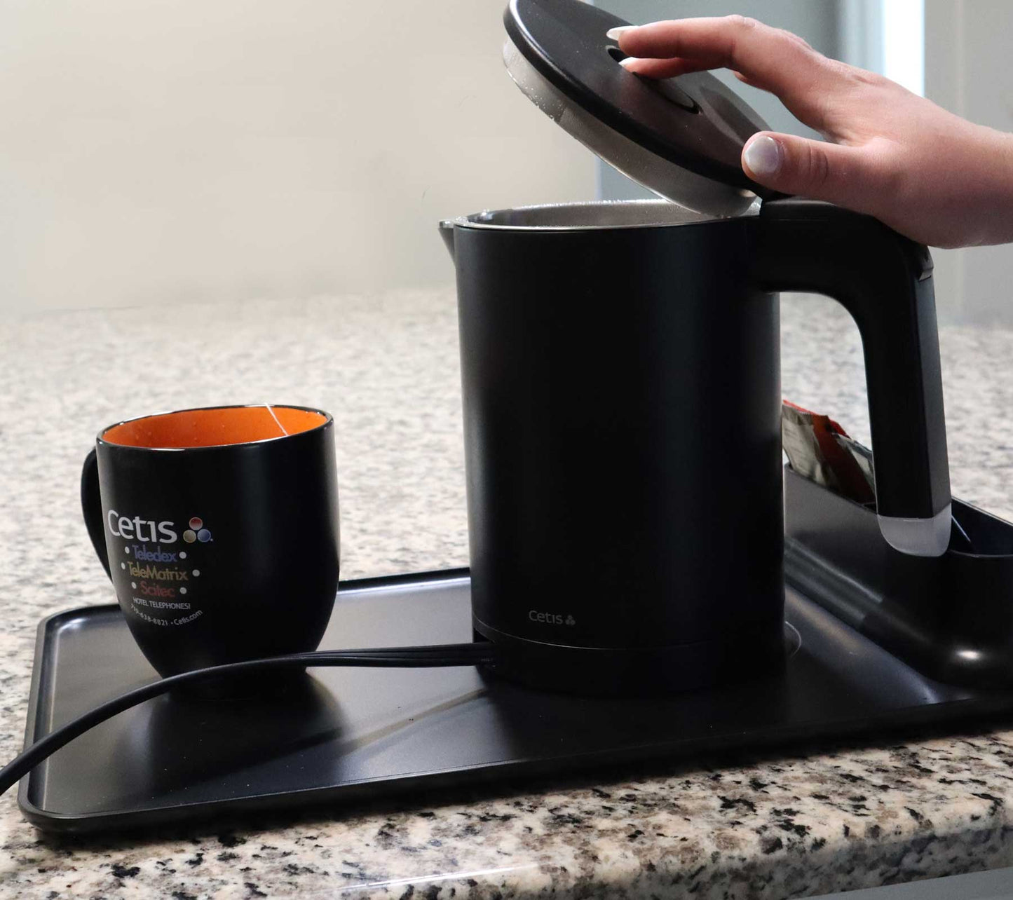 Valiant Products K-608 black electric kettle with anti-scalding insulation on a serving tray with a matching mug